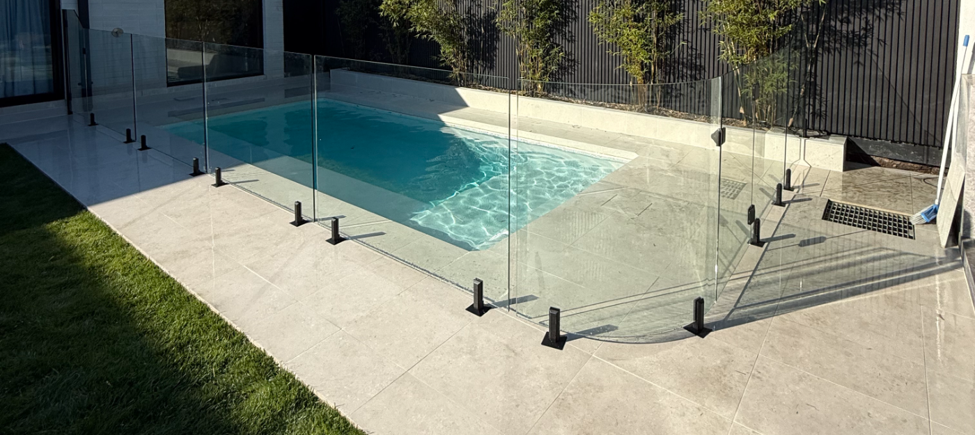 Glass pool fencing with dark timber slat wall